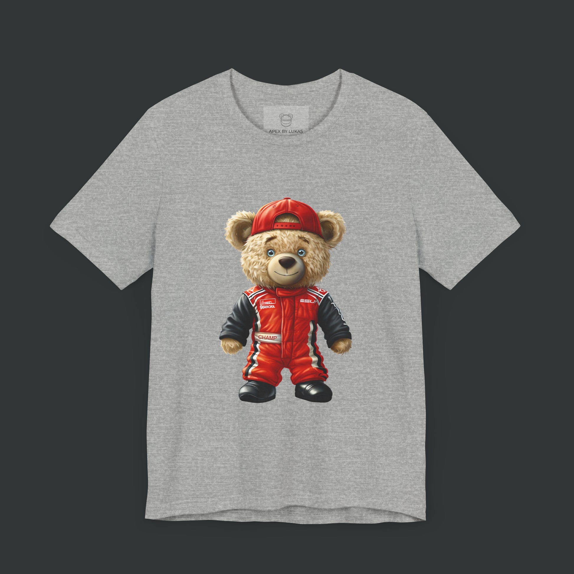 A teddy bear wearing a red karting suit with black accents and name patch "Champ", and a backwards worn red cap on a athletic heather color unisex t-shirt