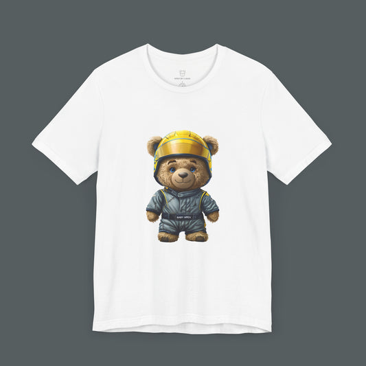 A rookie teddy bear wearing an oversized grey-blue karting racing suit and a yellow helmet on a white t-shirt